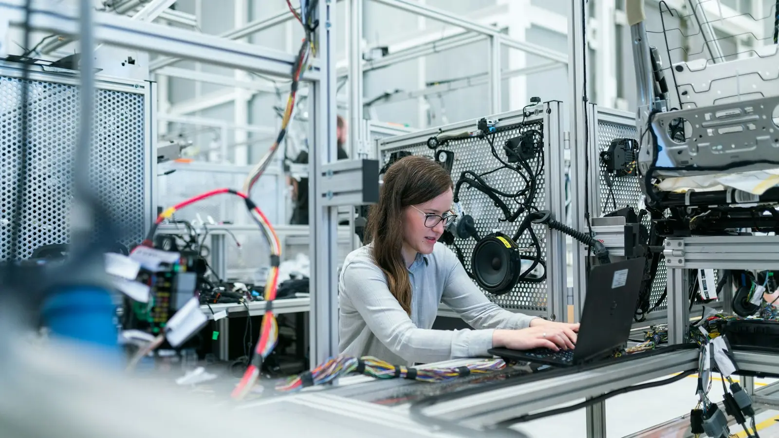 An engineer working at a laptop among production equipment