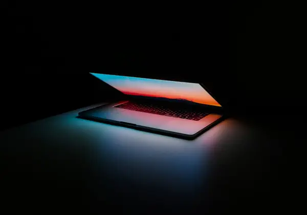 A laptop lit from the side in a dark room
